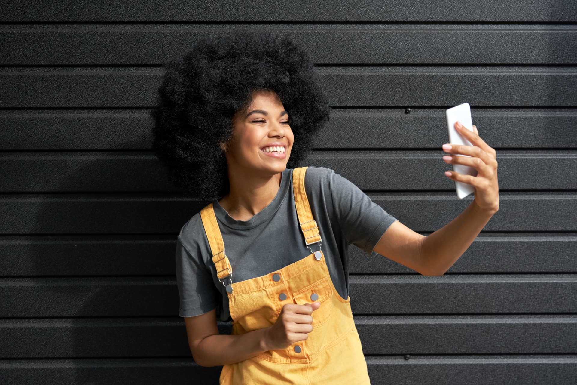 A young woman smiling as she records a video message on her phone